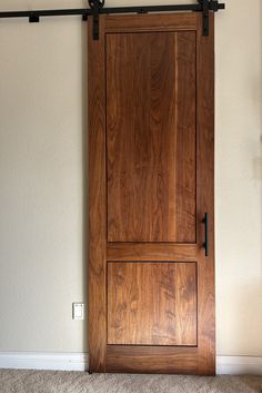 a wooden door with metal handles in the corner of a room, next to a carpeted floor