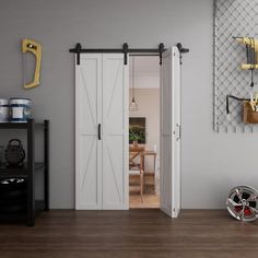 an open door to a kitchen and dining room with white walls, wood flooring and yellow hooks on the wall