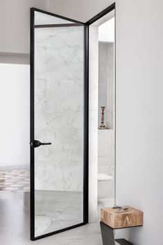 a bathroom with marble walls and flooring next to a wooden bench in front of a glass shower door