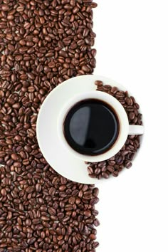 a cup of coffee on top of some coffee beans