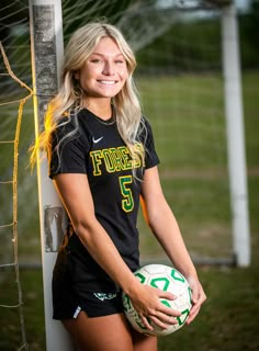 a woman holding a soccer ball in front of a goal