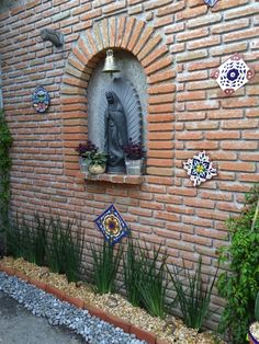 a brick wall with a statue and potted plants