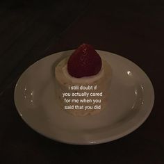 a white plate topped with a piece of cake and a strawberry on top of it