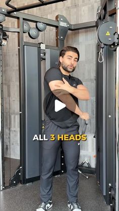 a man standing in front of a gym machine with his arms crossed and looking at the camera