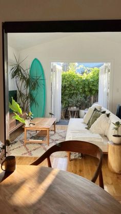 a living room filled with furniture and a surfboard in the back door window sill