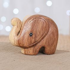 a small wooden elephant figurine sitting on top of a table next to a christmas tree