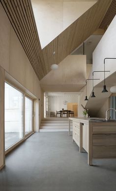 an empty kitchen and dining area in a house with wood ceilinging, white walls, and large open floor to ceiling windows