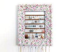 a wall mounted jewelry rack with flowers on it