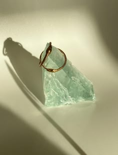 a gold ring sitting on top of a piece of green glass next to a shadow