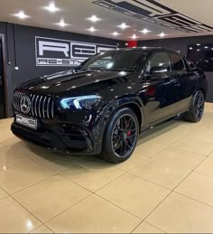 a black mercedes suv parked in a showroom