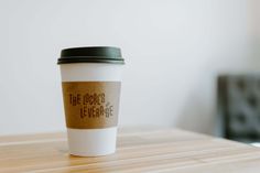 a coffee cup sitting on top of a wooden table next to a black and white chair