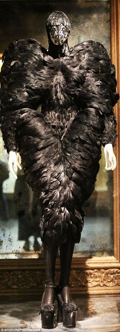 a woman's dress made out of feathers in front of a painting