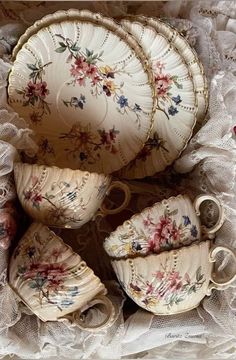 an assortment of porcelain dishes and cups on a lace tablecloth