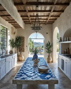 a kitchen with a table and potted plants on the counter top in front of an arched doorway