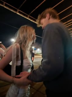 a man and woman standing next to each other in front of a building at night