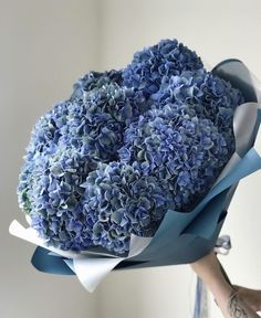 a woman holding a bouquet of blue flowers