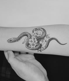 a woman's arm with a snake and flowers tattoo on the left side of her arm