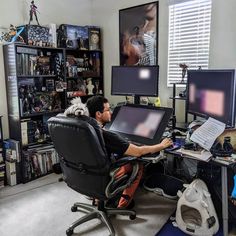 a man sitting at a computer desk in front of two monitors