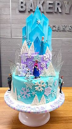 a frozen princess cake on a table with figurines around it and the name bakery cakes