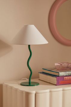 a lamp sitting on top of a white table next to a book and a mirror