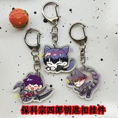 two key chains with anime characters on them sitting next to an orange and some other items