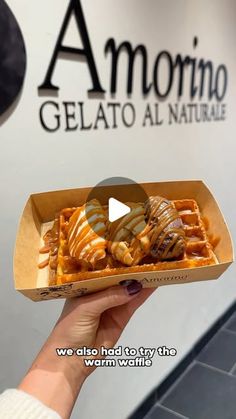 someone is holding up a waffle with syrup and chocolate on it in front of the gelato al naturale sign