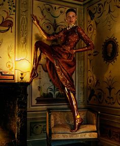 a woman is standing on top of a chair in a room with ornate wallpaper