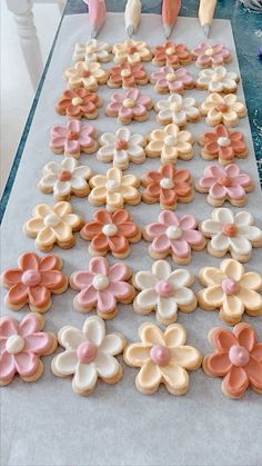 decorated cookies sitting on top of a table next to pink and white flowers in the shape of hearts