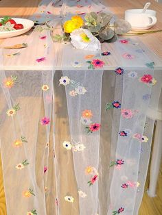 the table is covered with sheer fabric and flowers