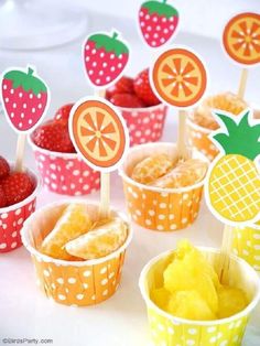 cupcakes with strawberries and orange slices on them are arranged in paper cups