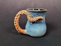 a blue and brown cup with an octopus on the inside is sitting on a black surface