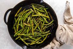 asparagus being cooked in a skillet on a white counter top with a cloth