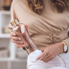 a woman is holding a bottle with some liquid in it