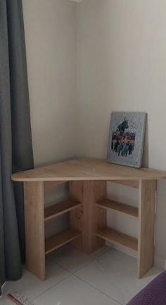 a small wooden desk in front of a window with curtains on the side and an open book shelf