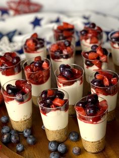 small desserts are arranged on a wooden platter with blueberries and strawberries