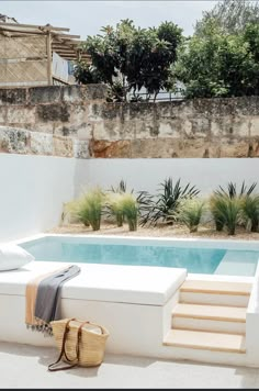 an outdoor swimming pool with steps leading up to it and a bag on the ground