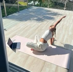 a woman is doing yoga outside on her laptop