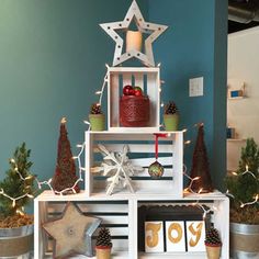 a christmas tree made out of crates with decorations and lights on it in a room