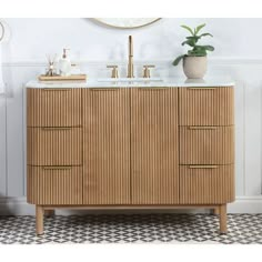 a bathroom vanity with two sinks and a mirror on the wall next to a potted plant