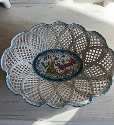 a decorative glass dish on a white wooden table with sunlight coming through the window behind it