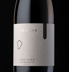 a bottle of the lane heritage chardonnay wine on a black background with a white label