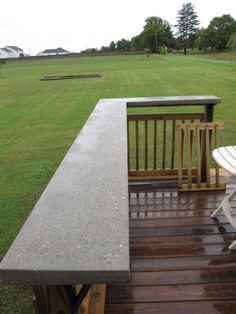 a white chair sitting on top of a wooden deck next to a lush green field