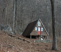 a small cabin sitting in the middle of a forest next to a pile of leaves