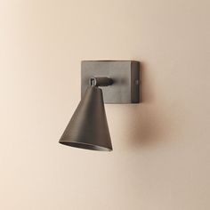 a wall light mounted on the side of a wall next to a white wall with a black cone shade