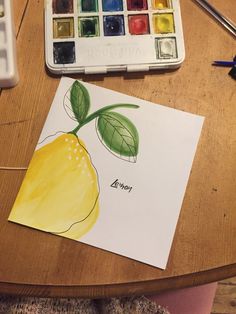 a drawing of a lemon on top of a piece of paper next to some watercolor paints