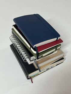 a stack of notebooks sitting next to each other on top of a white table