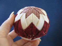 a hand is holding a red and white ball ornament in it's palm