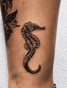 a black and white photo of a sea horse tattoo