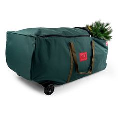 a green bag with a christmas tree in it on top of a black dolly wheel