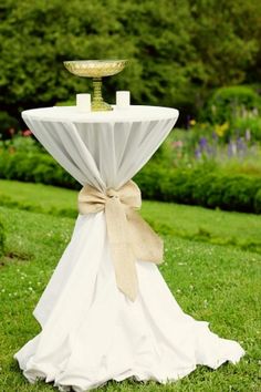 a white table topped with a cake on top of a lush green field